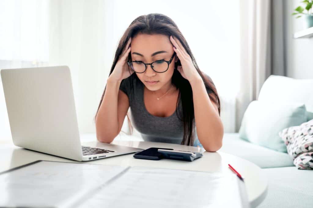 Desperate and worried asian woman calculating taxes bills at home